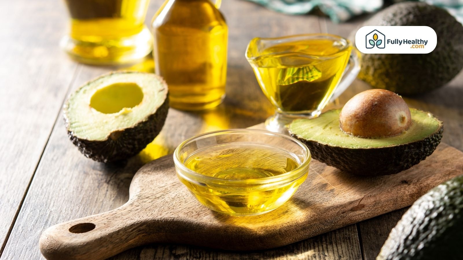 Fresh avocado halves with small bowls of avocado oil on board