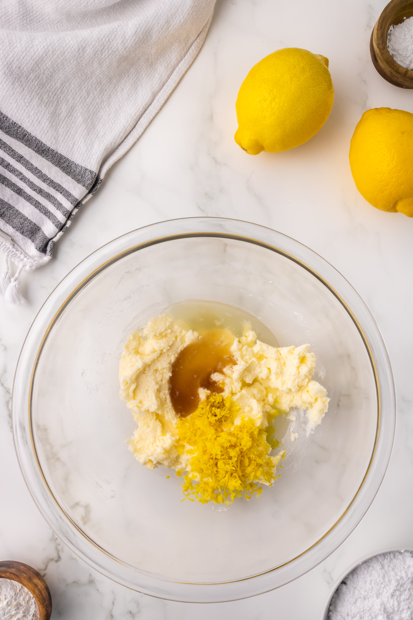 lemon zest, lemon juice, vanilla extract, and lemon extract added to bowl of sugar and butter