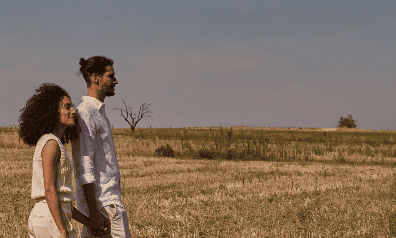 Couple walking in an open field praying that the Lord Bless them.