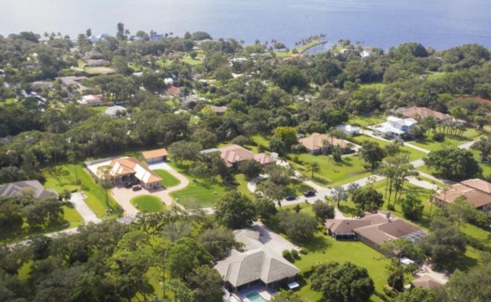 The image features a sprawling estate-style home with contemporary architecture, set against the backdrop of the Caloosahatchee River in North Fort Myers. The property boasts waterfront terraces, ideal for prospective property consumers interested in luxury real estate in the Skyline Woods community.