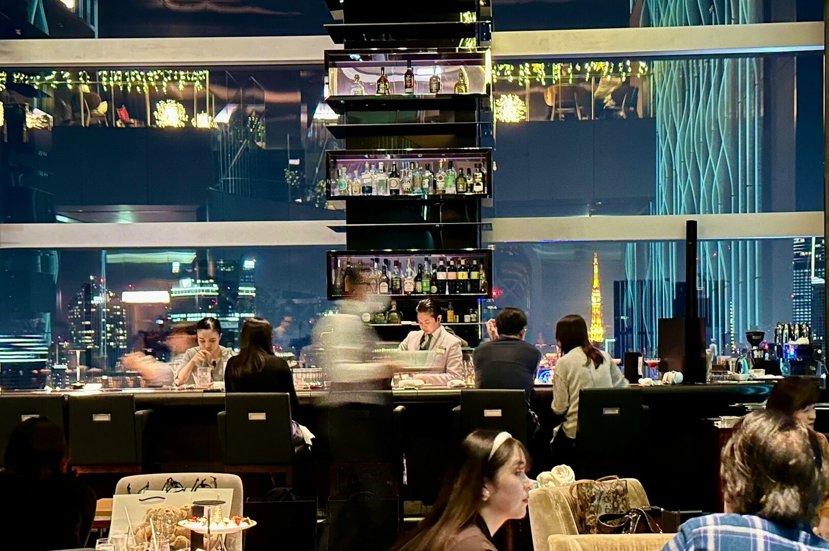  Guests seated at tables in a fine dining restaurant, overlooking the vibrant cityscape of Singapore.