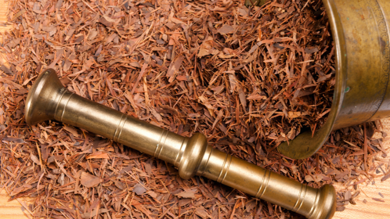 Auf einer rustikalen Holzoberfläche liegen getrocknete Stücke der Lapacho-Rinde, die für die Zubereitung von Lapachotee verwendet werden. Diese Rinde stammt vom Lapacho-Baum, auch bekannt als "Baum des Lebens", und ist bekannt für ihre heilenden Eigenschaften und ihren einzigartigen Geschmack.