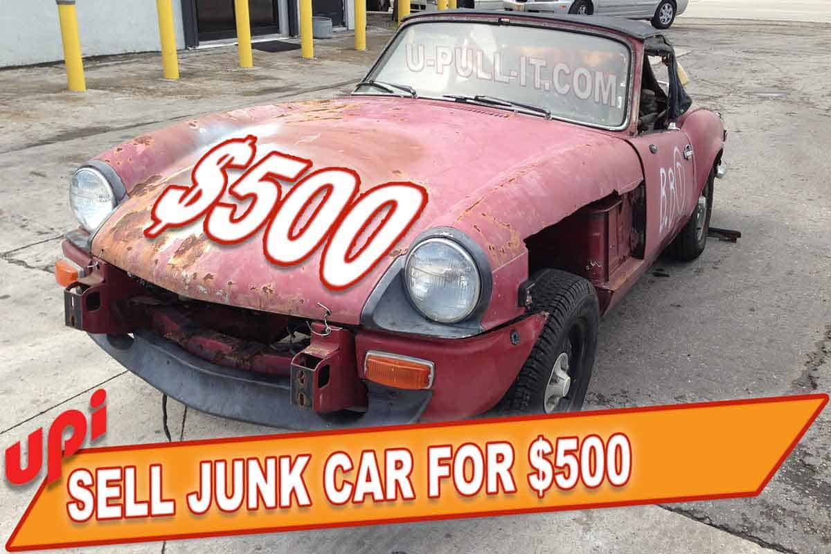A junk car with a sign saying "500 cash for junk cars"
