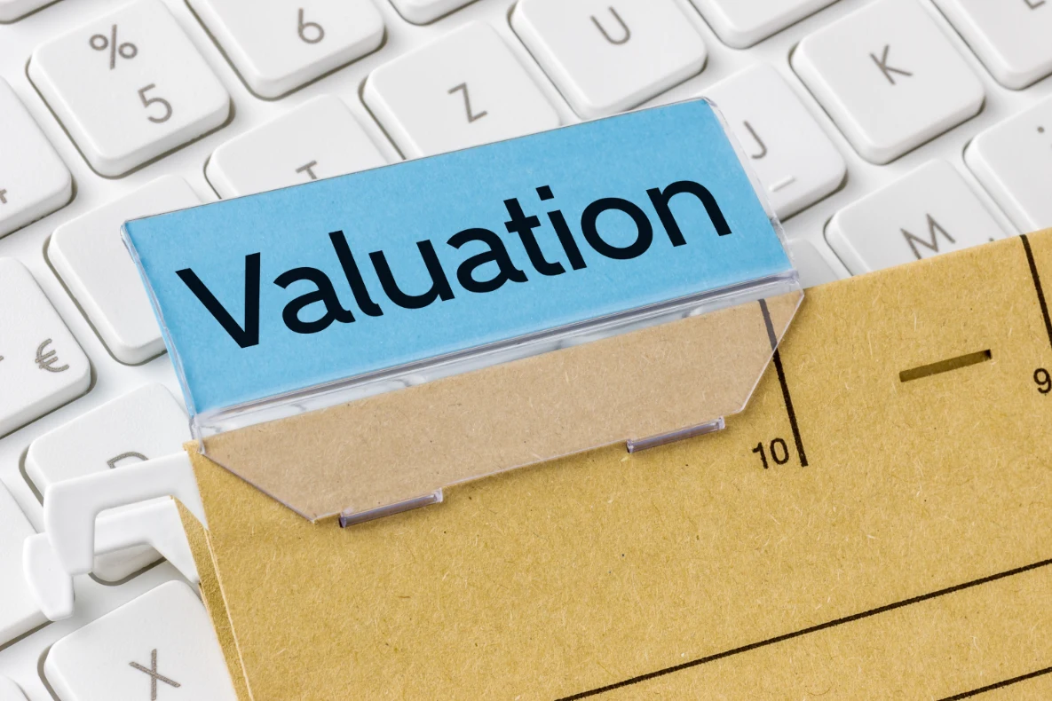 A blue label with the word "Valuation" printed in black rests on a manila folder tab, containing likely business valuation resources.