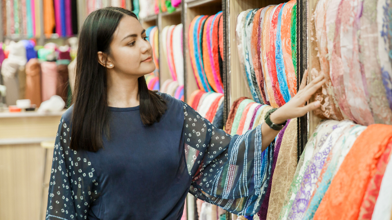 A lady is looking at a fabric in a clothing store