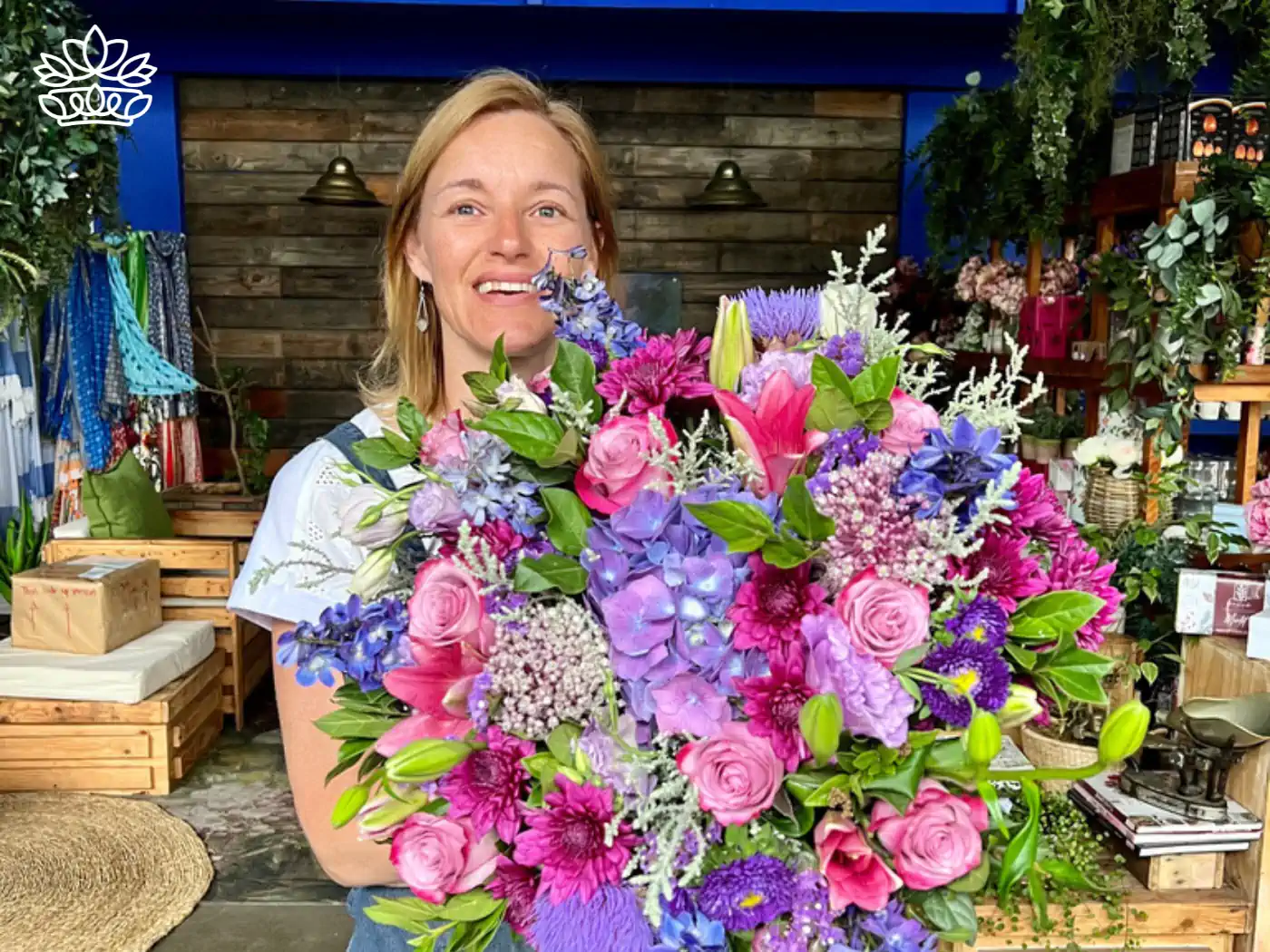 Cheerful woman holding a luxurious blue and pink floral arrangement inside a flower shop, from the Fabulous Flowers and Gifts collection.