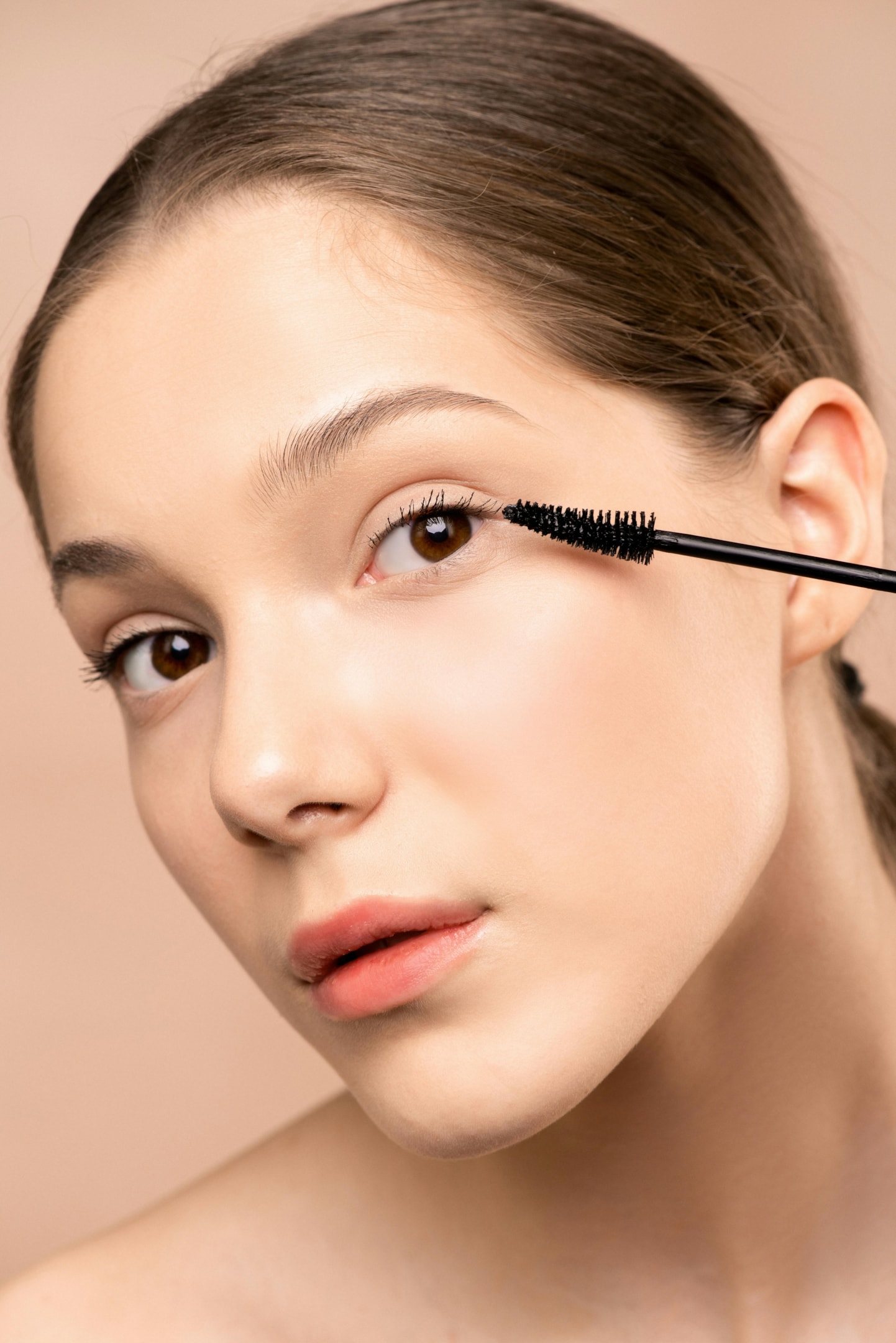 Closeup of a woman applying a lash brush to her lashes