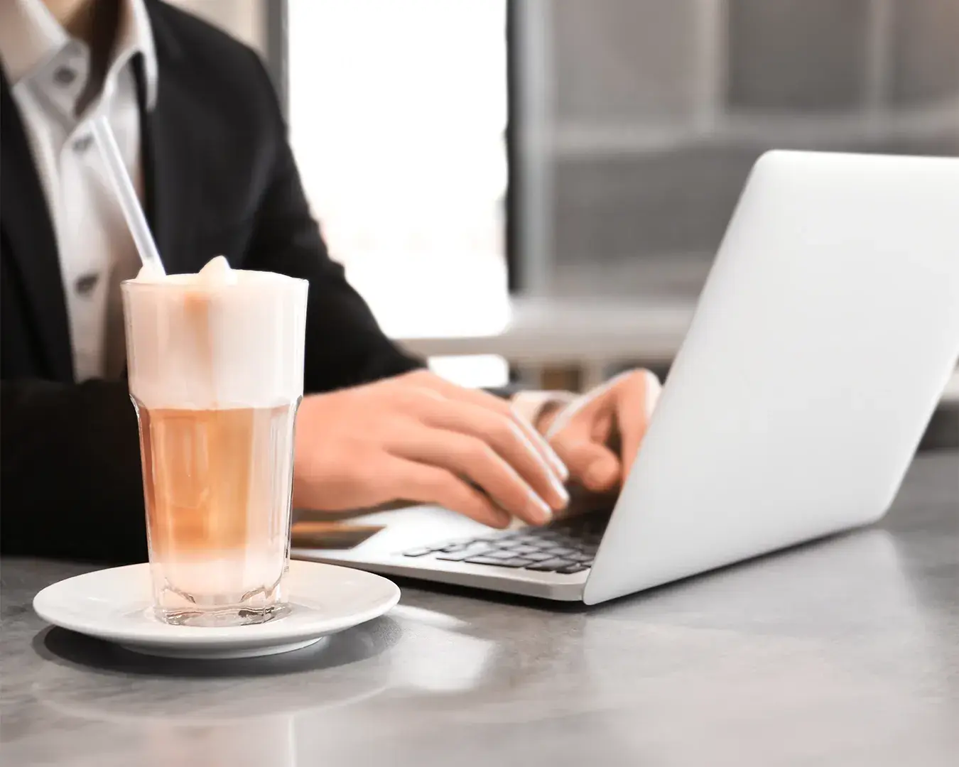 Restaurant owner managing automated email campaigns on laptop with latte in modern café workspace