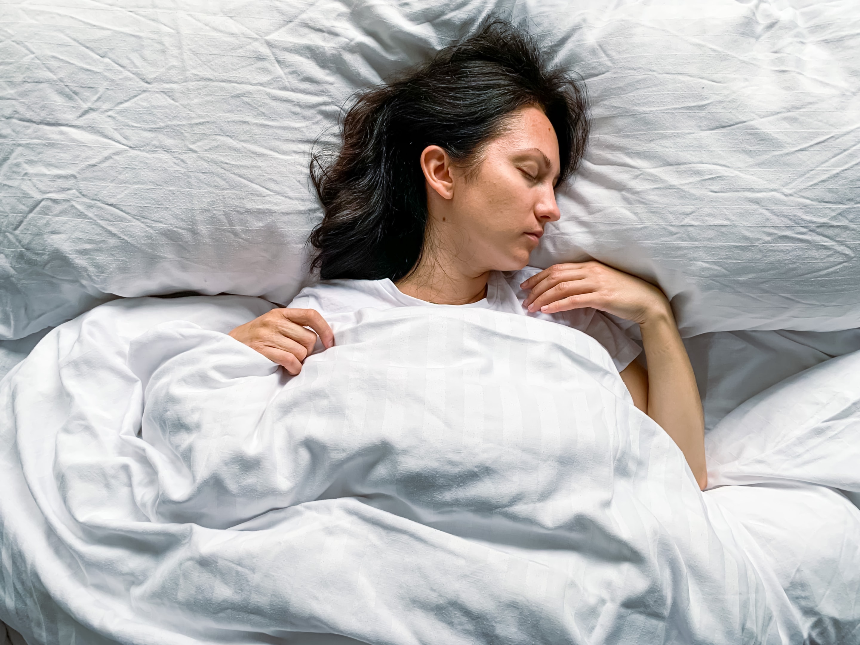 Woman sleeping in bed right after wisdom teeth removal wondering "can you talk after wisdom teeth removal?"