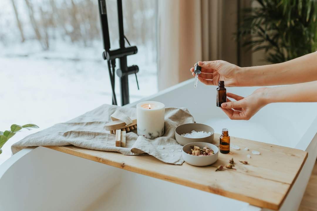 Relaxing bathtub setup with essential oils, candle, and bath salts, creating a soothing spa atmosphere at home.