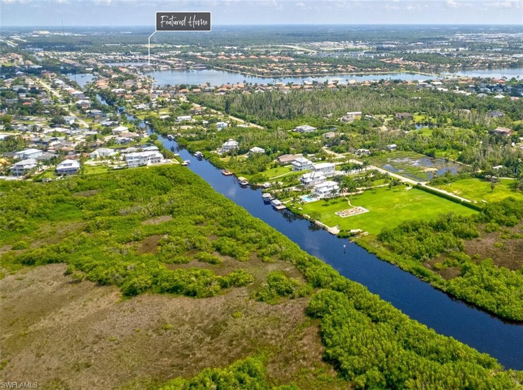 An aerial view of the Hidden Harbor community in Fort Myers, Florida, showcases luxury homes lining the waterfront, with boat docks and lush landscaping visible. The serene environment is complemented by resort-style amenities, including a swimming pool and clubhouse, highlighting the unique lifestyle offered in this gated neighborhood.