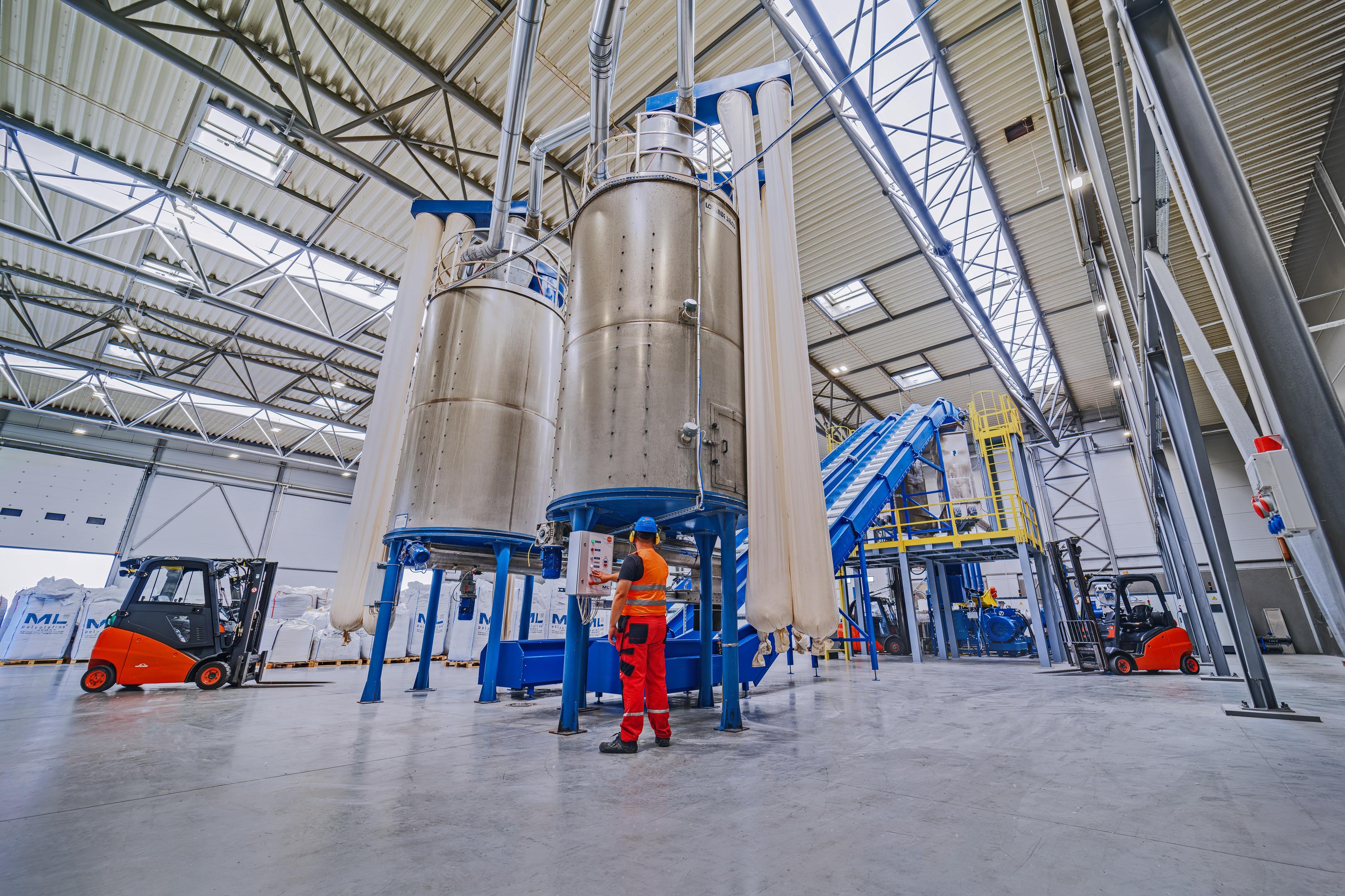 Na zdjęciu znajduje się linia produkcyjna do recyklingu tworzyw sztucznych, wyposażona w taśmociągi oraz maszyny do granulacji, które umożliwiają przetwarzanie odpadów w surowce do ponownego wykorzystania. Taki proces jest kluczowy w gospodarce o obiegu zamkniętym, przyczyniając się do zmniejszenia odpadów i oszczędności zasobów naturalnych.