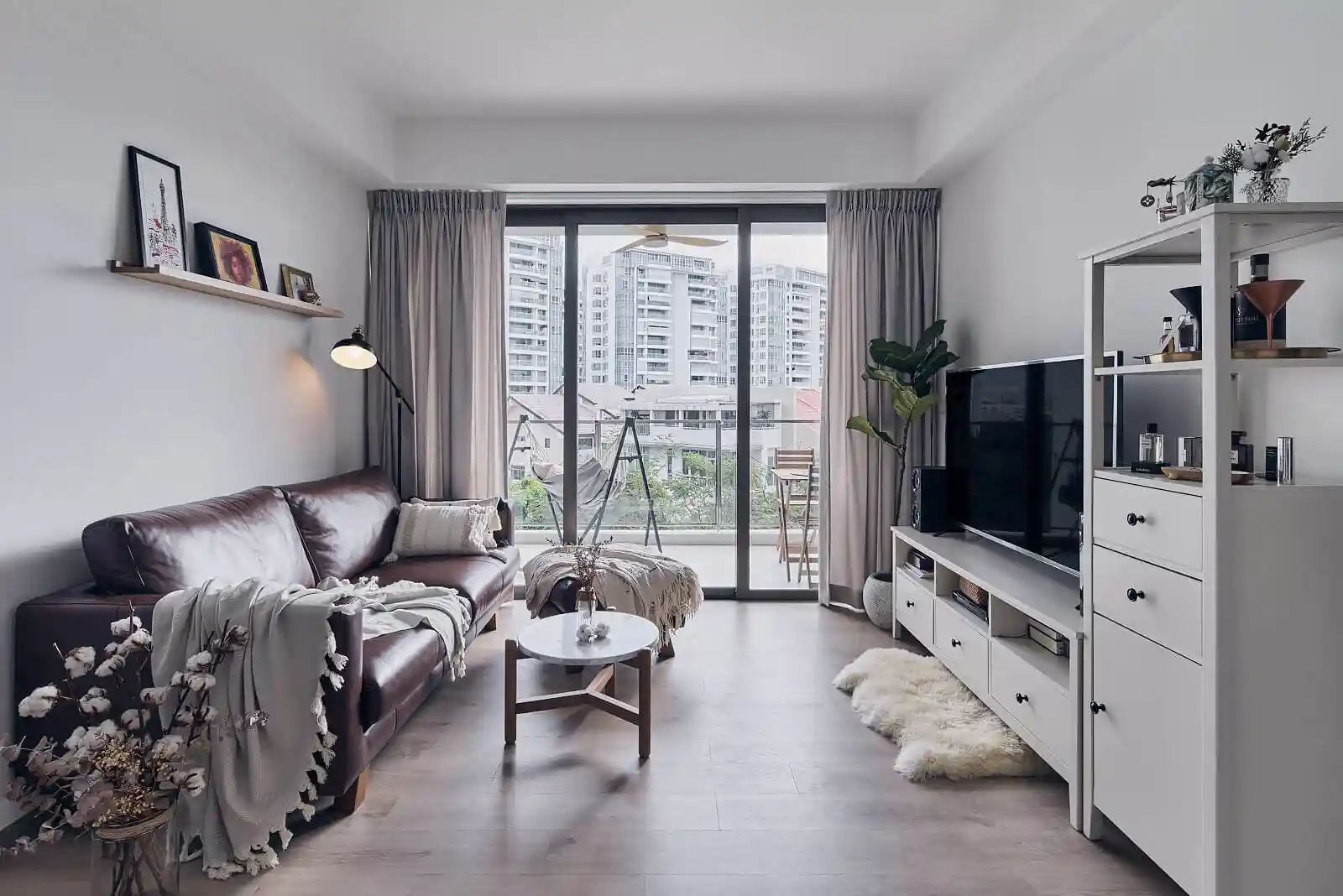 Minimalist KL condo living room with leather sofa and skyline view exemplifying modern condo interior design.