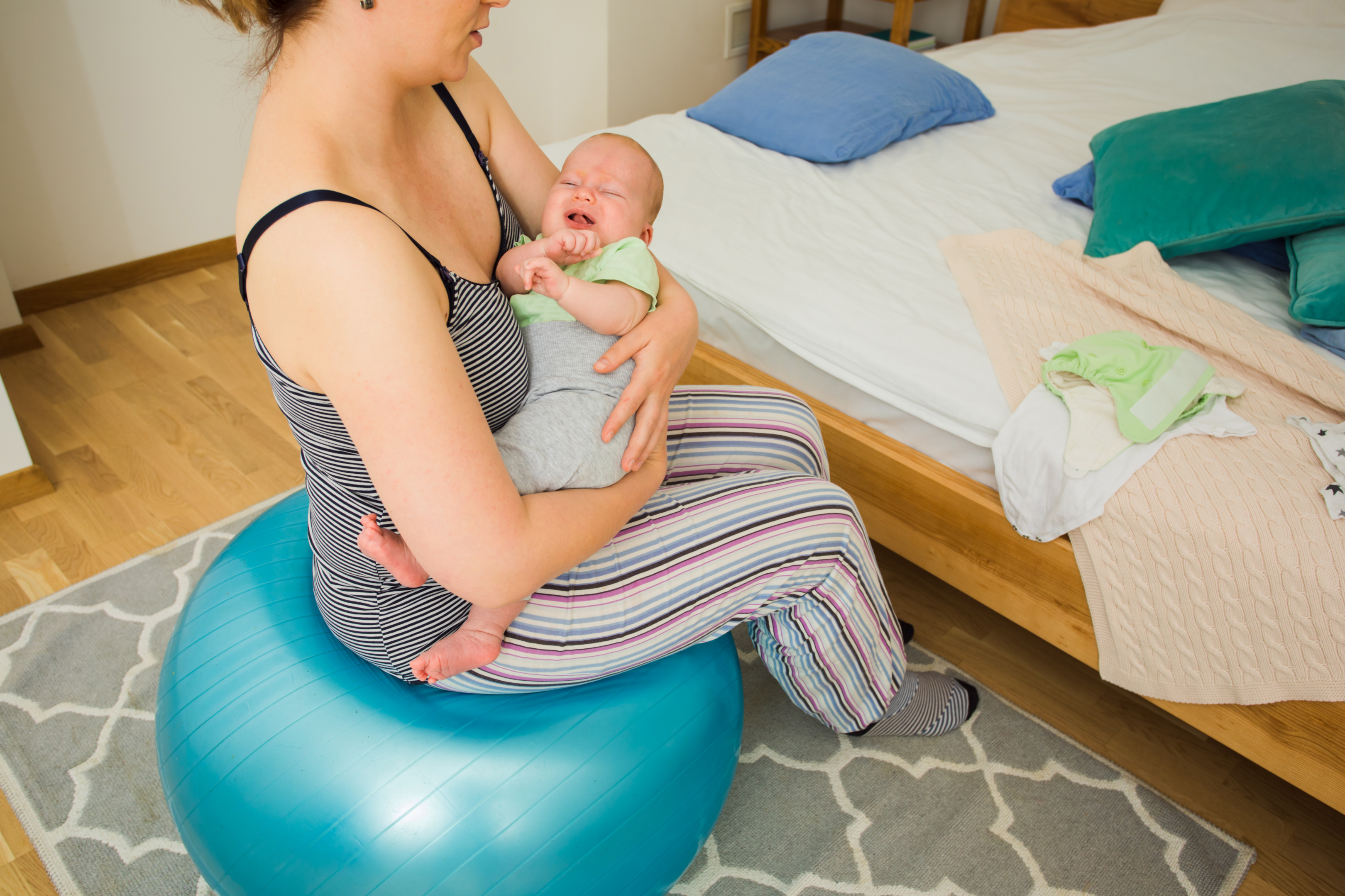 En kvinde, der holder en baby, mens han sidder komfortabelt på en fødselsbold.