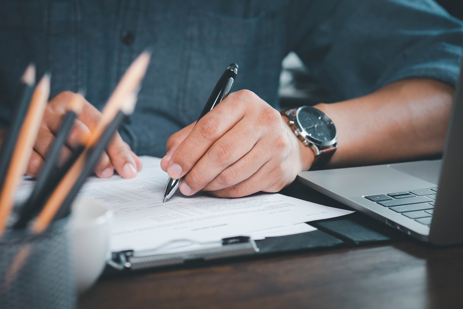 A close-up of a hand using a pen to answer a scorecard.