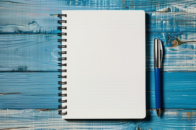 A notebook and a pen, against a blue background.