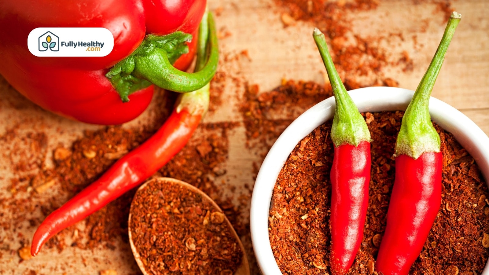 Red chili peppers with crushed flakes in bowl and wooden spoon