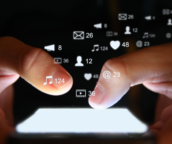Fingers above a cell phone typing on a social media platform