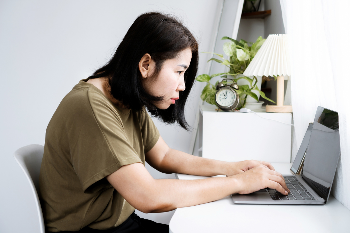 Focused Filipina developer typing on laptop while completing a timed coding test at home