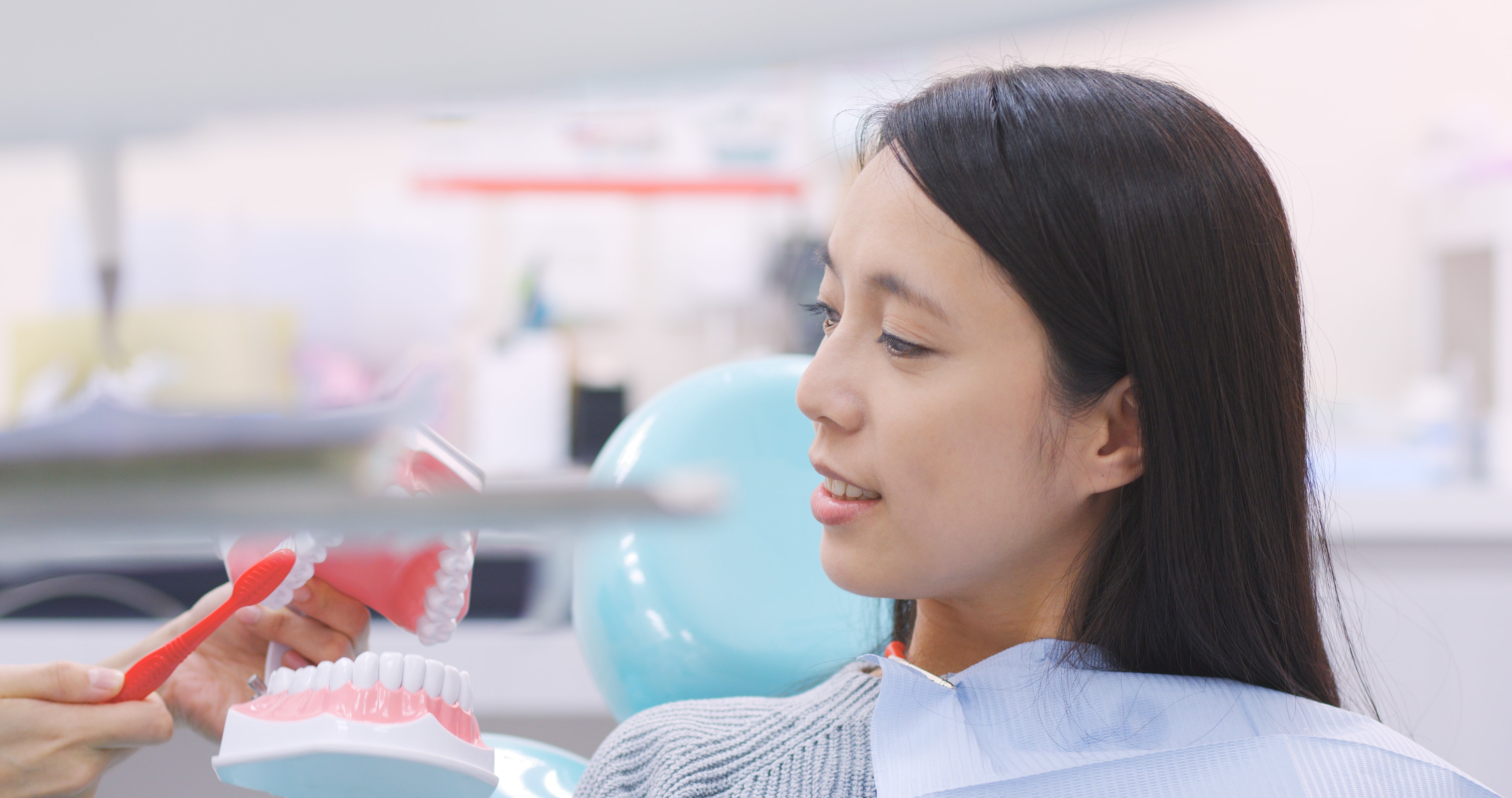 A young woman in a dental share being consulted abut dental implants with a model mouth