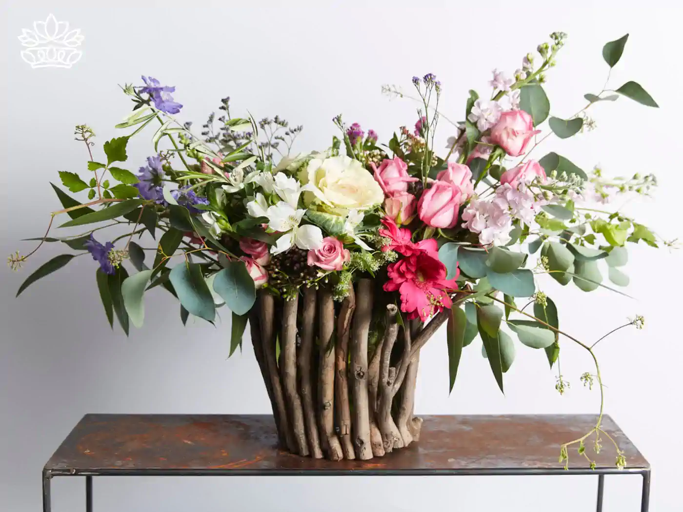 A rustic wooden vase filled with a delicate blend of pink roses, white blossoms, and subtle blue flowers, presenting a natural yet refined look perfect for a front desk reception desk.