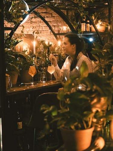 Woman surrounded by plants a cozy bar