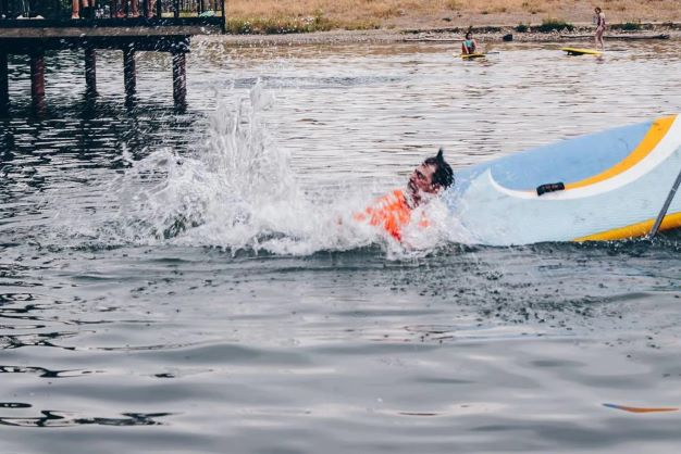 man falling off paddle board