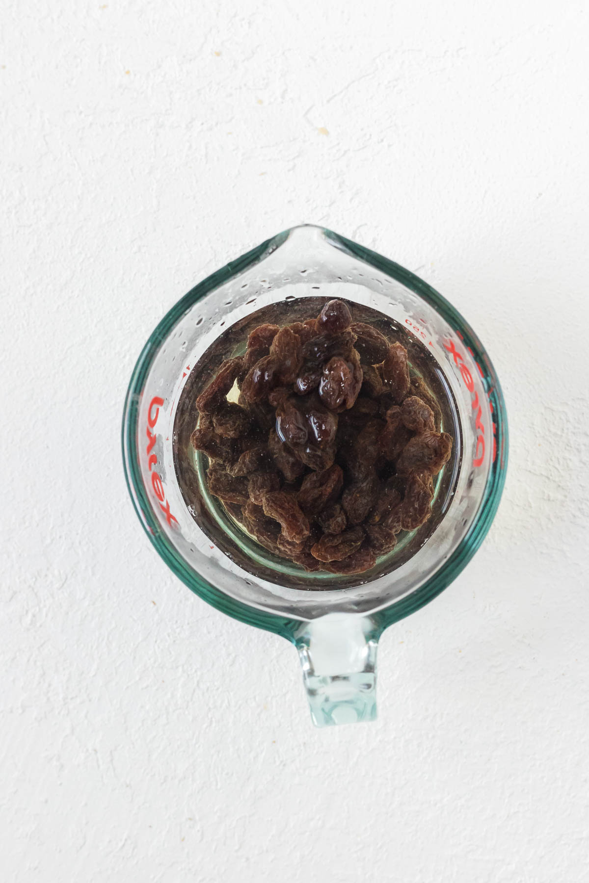 a liquid measuring cup with hot water and raisins