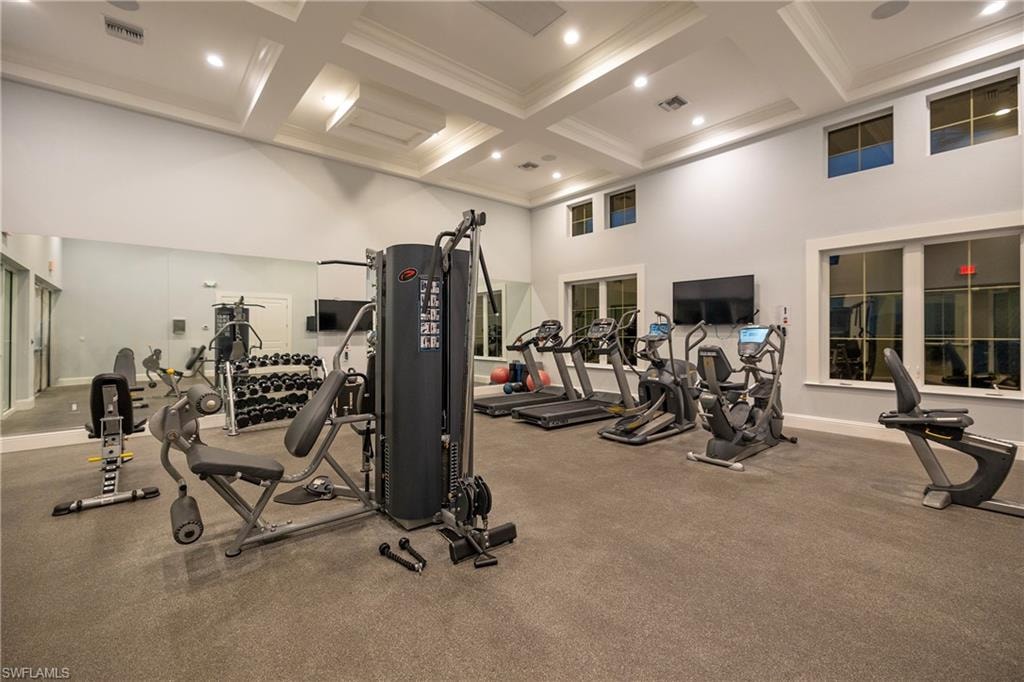 The image depicts a resort-style swimming pool complex located in the Hidden Harbor community of Fort Myers, Florida. The area features a spacious pool surrounded by lush landscaping, lounge areas, and a cozy fire pit, creating a serene environment for residents to relax and enjoy the luxurious lifestyle.