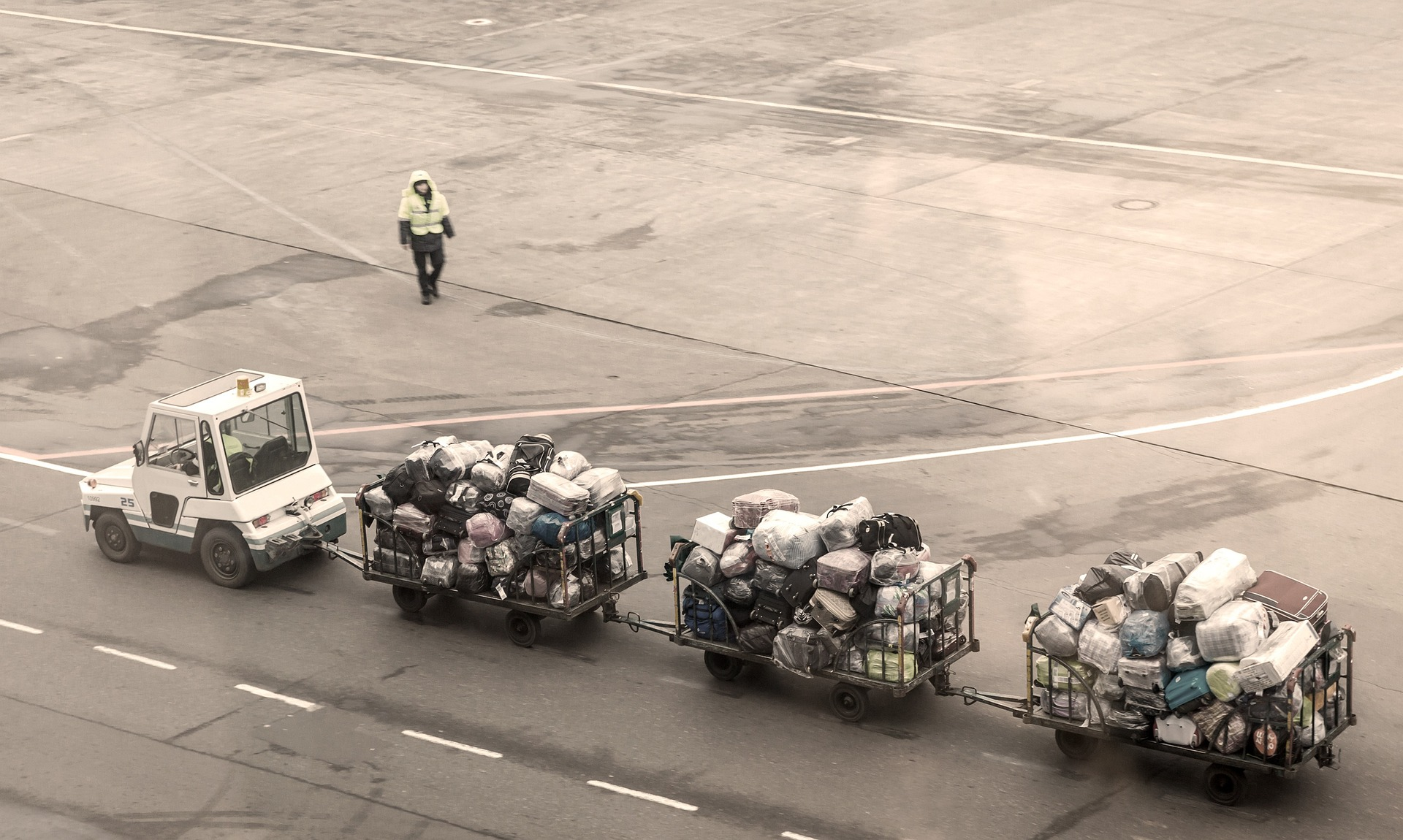 A small car towing carts full of checked-in luggage.