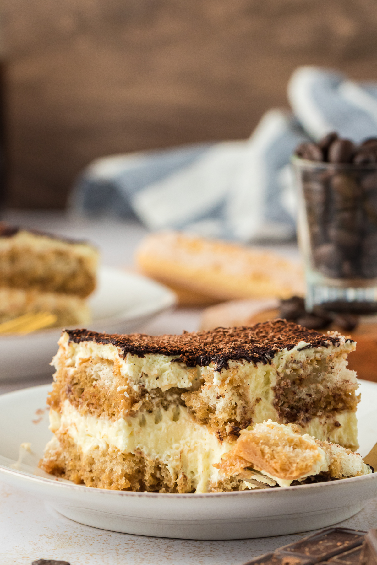 Tiramisu slice on a plate with a fork and a bite taken out of it