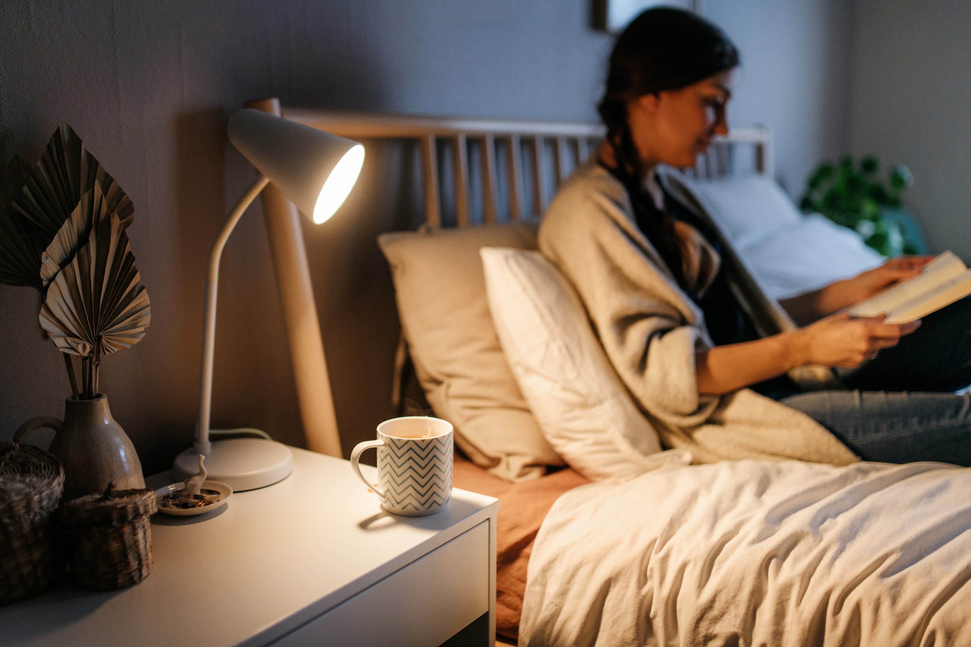 Guest holding reading material accommodated with bedside tables for enough surface space to store belongings 