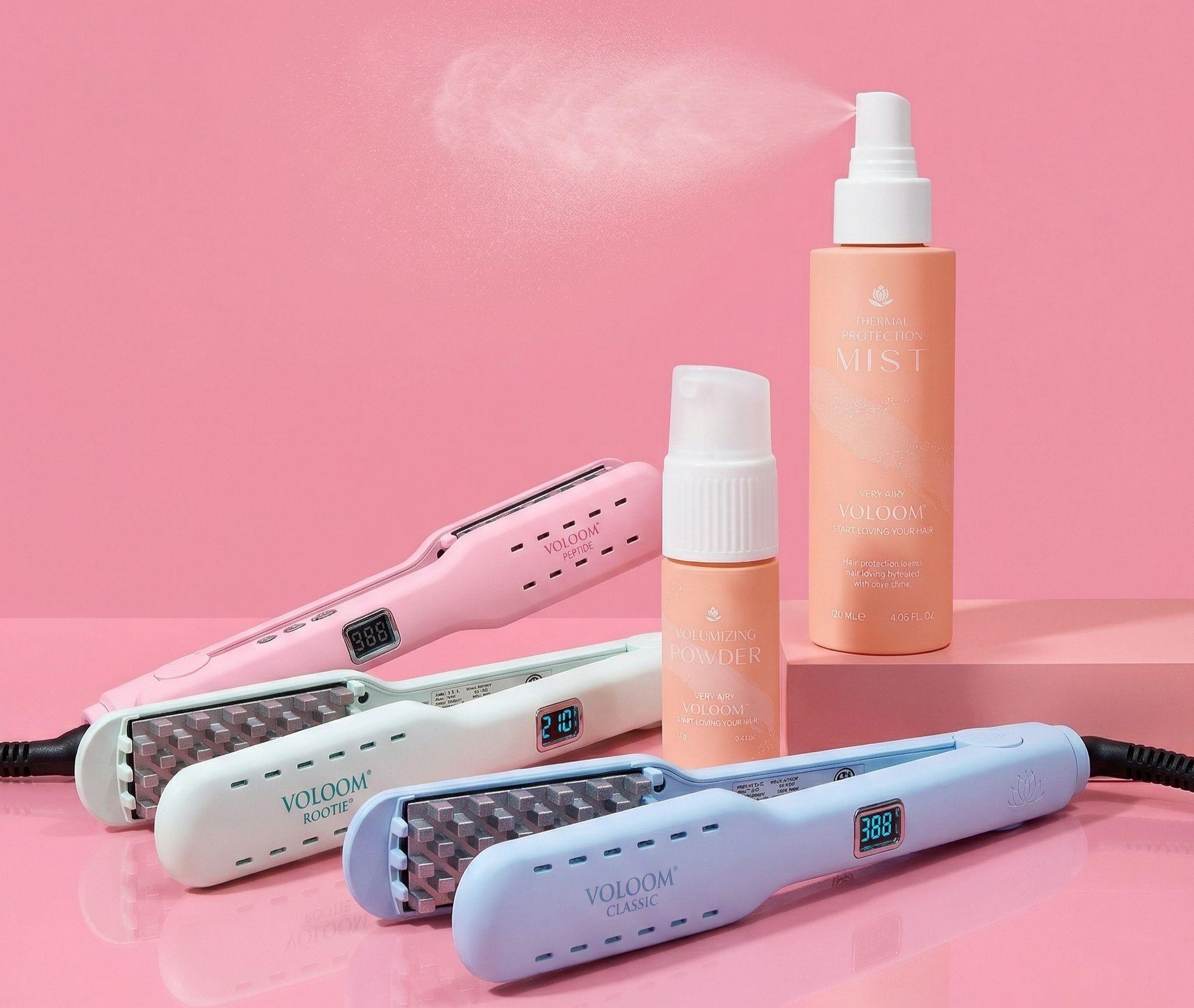 A flat lay showcases an array of hair styling tools and volumizing products, including a VOLOOM volumizing iron, heat protection and texturizing sprays, perfect for achieving bouncy, voluminous hair. The arrangement emphasizes various options for enhancing hair volume, suitable for different hair types, from fine to thick.