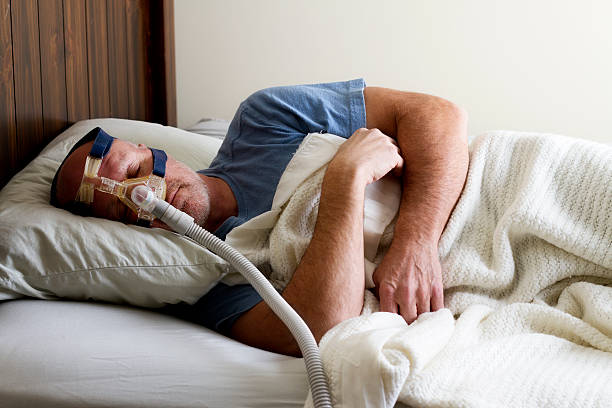 A photo of a man sleeping while having a CPAP therapy 