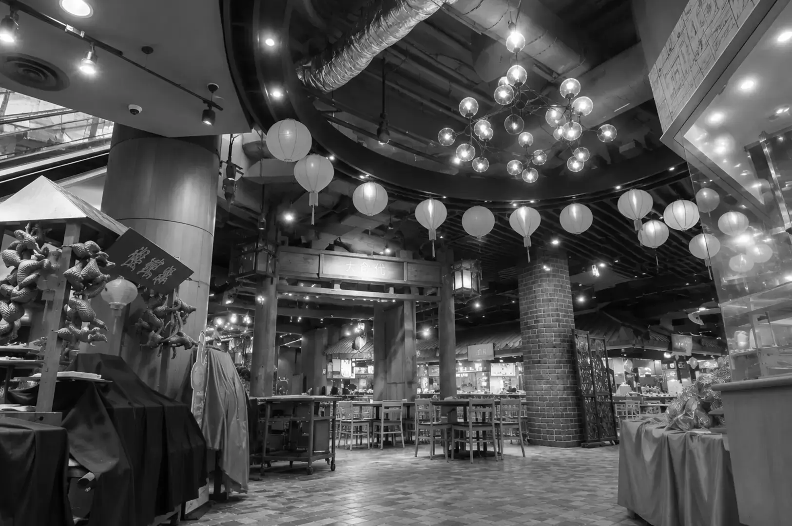 A spacious food-centre interior with wooden tables, hanging lanterns, decorative lights, and traditional Asian-style décor.