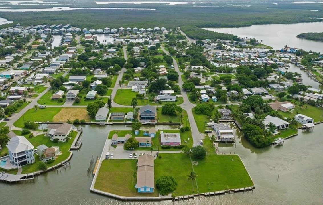 An aerial view showcases the picturesque Goodland waterfront community in Florida, featuring homes along the canals with boats dotting the water, highlighting the ideal blend of relaxation and convenience. This vibrant area offers ample space for entertaining and direct access to the serene surroundings, making it a rare opportunity for potential buyers seeking homes for sale in this charming locale.