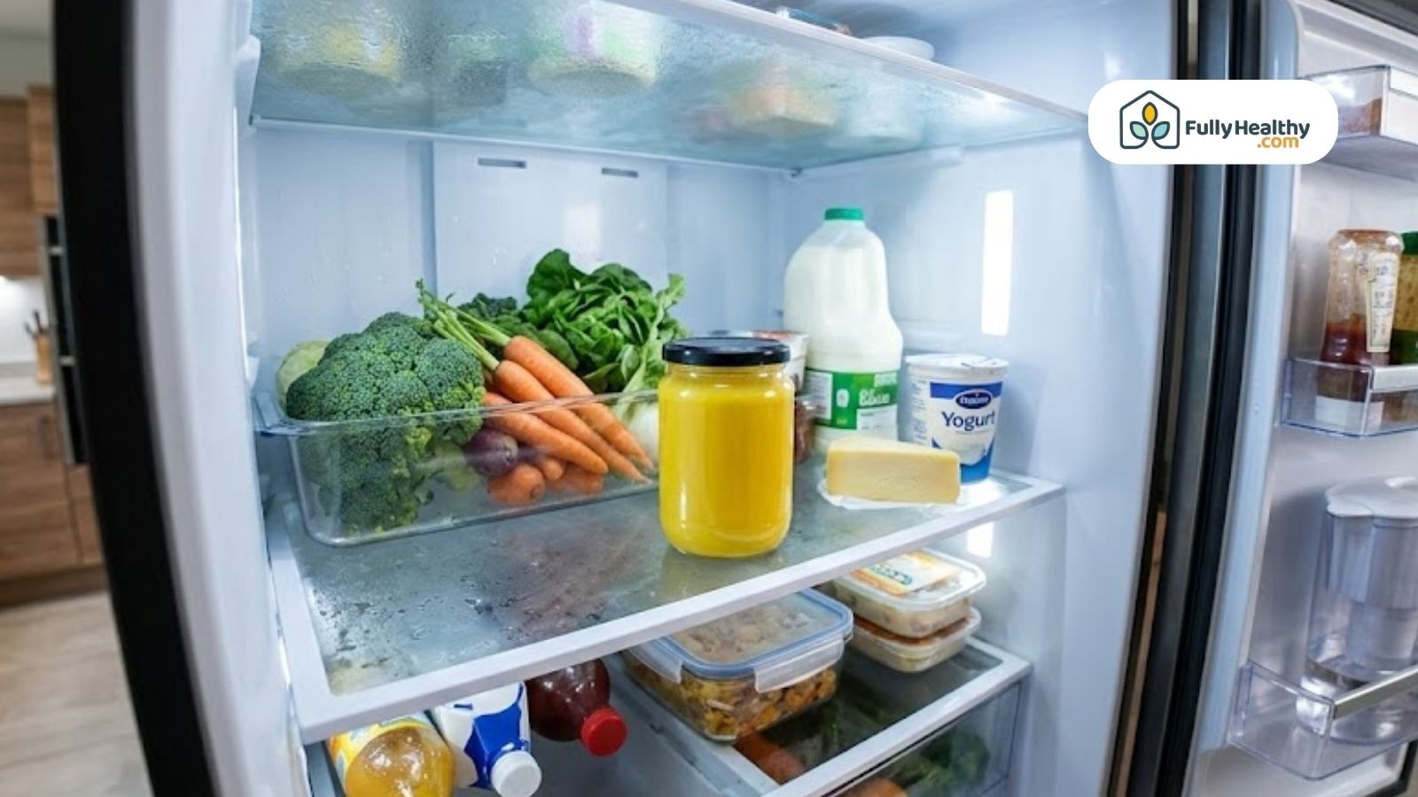 Jar of ghee stored inside a refrigerator shelf next to vegetables and dairy products.