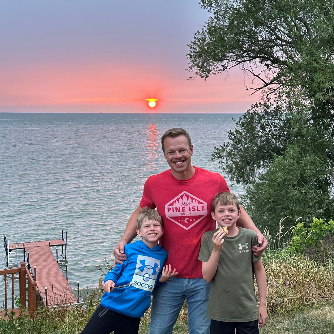 Dad and his two sons standing by a lake at sunset