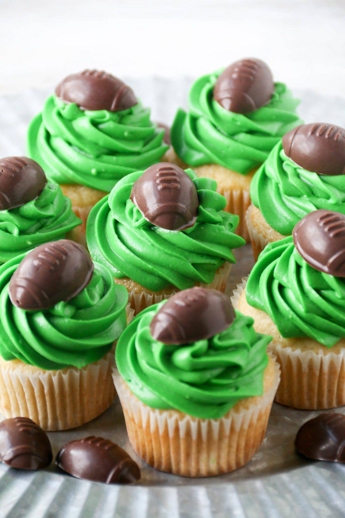 vanilla cupcakess with green frosting and topped with chocolate footballs