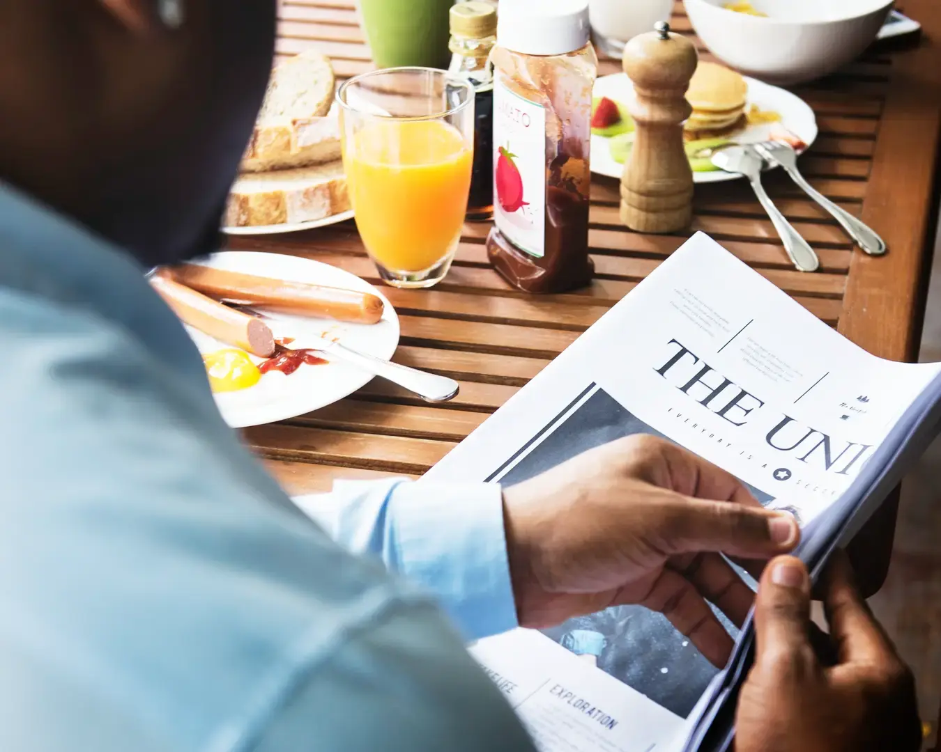 Customer reviewing a restaurant publication at a dining table, representing hospitality experience and brand perception