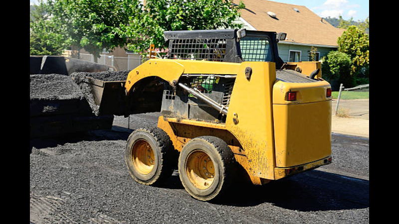 A skid steer engaging in roadwork. 