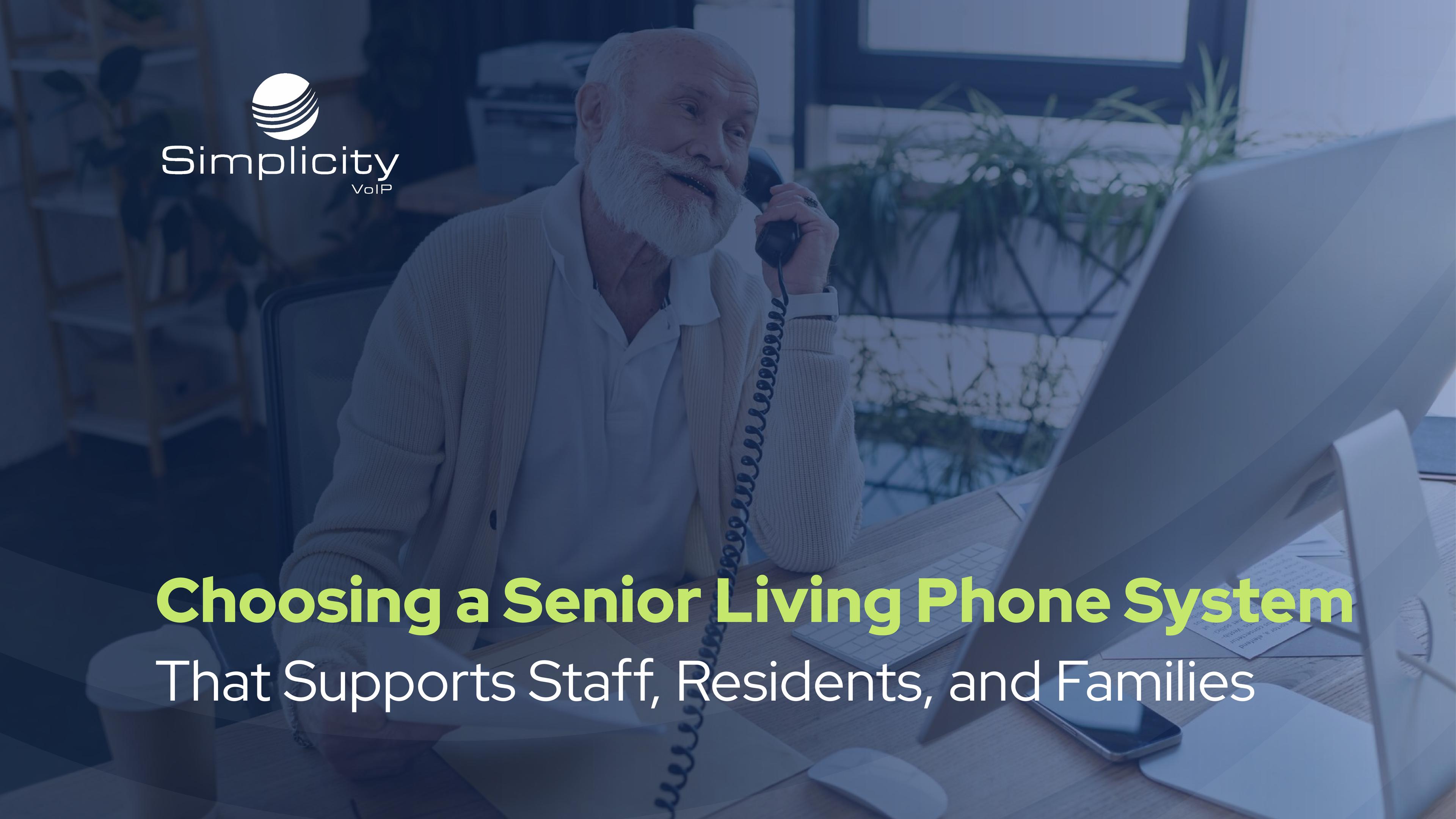 Man sitting at desk with businessman looking at options for the senior living phone system that fits best. 