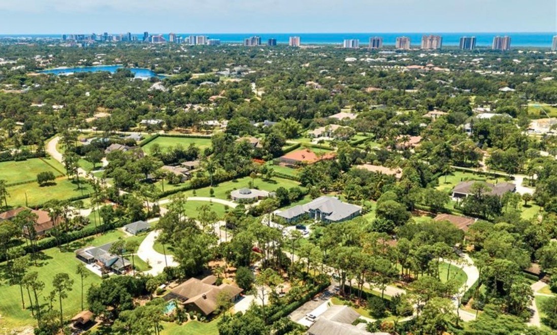 An aerial view of the prestigious Pine Ridge community showcases sprawling estate lots nestled amidst lush landscaping, highlighting the luxurious outdoor living spaces and stunning custom homes. This image captures the essence of resort-style living in the sought-after Pine Ridge Estates neighborhood, emphasizing the expansive properties and elegant surroundings.