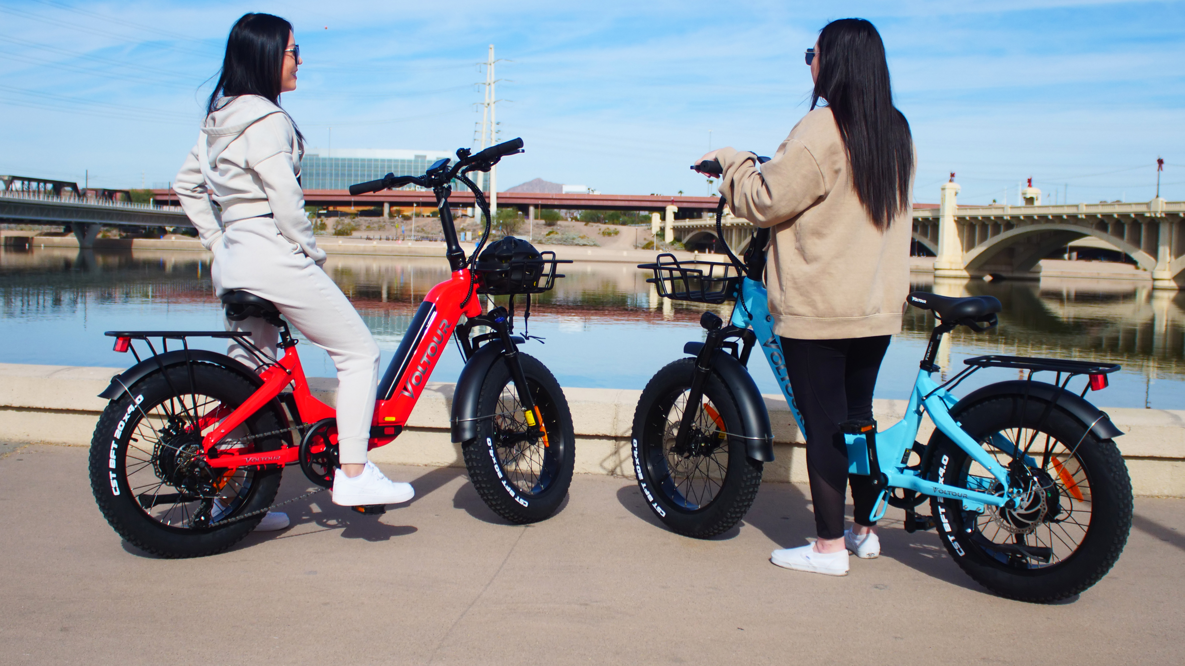 two people on ebike in front of river and bridges