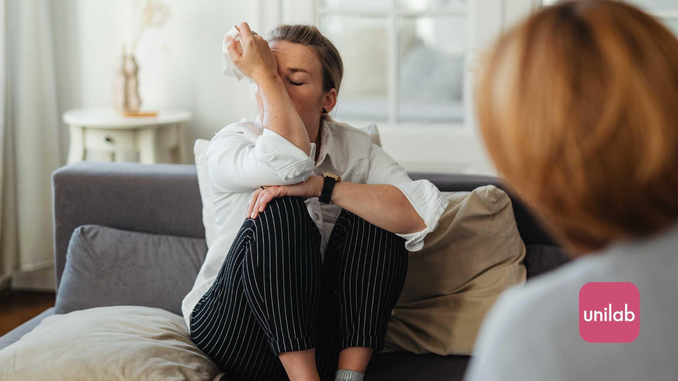 Women upset an crying in the couch with tissues