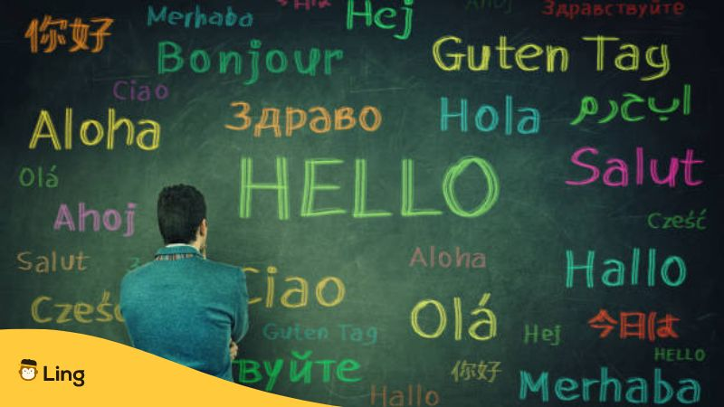 Different languages on a a greenboard with a man standing