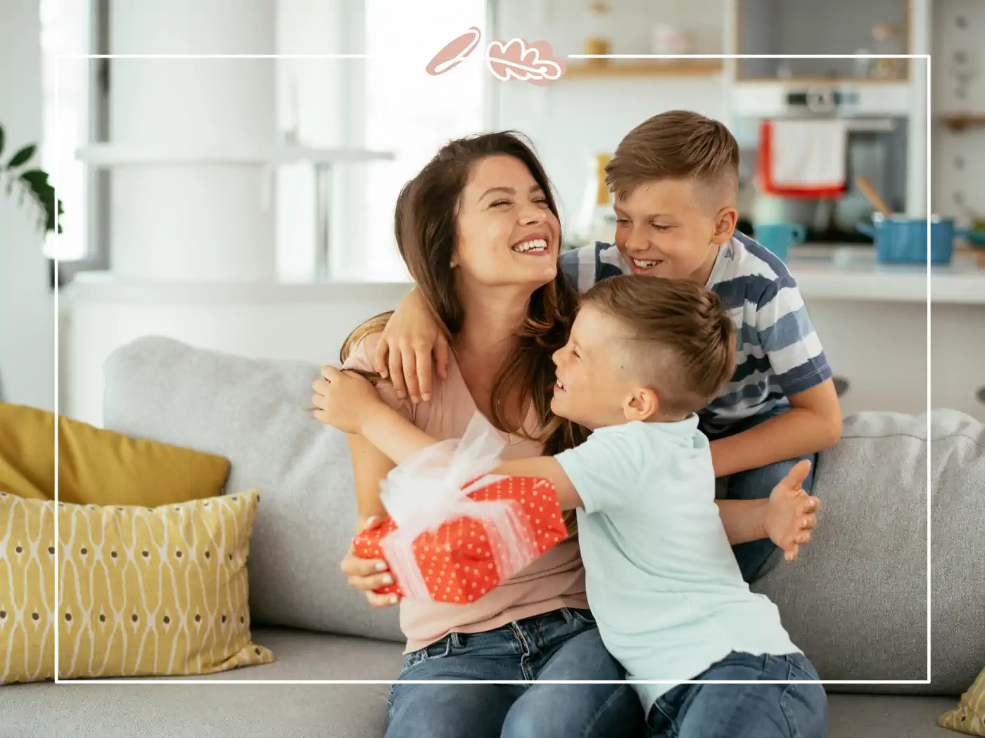 Woman hugging two young boys on a couch, with one boy holding a red gift box, Fabulous Flowers and Gifts