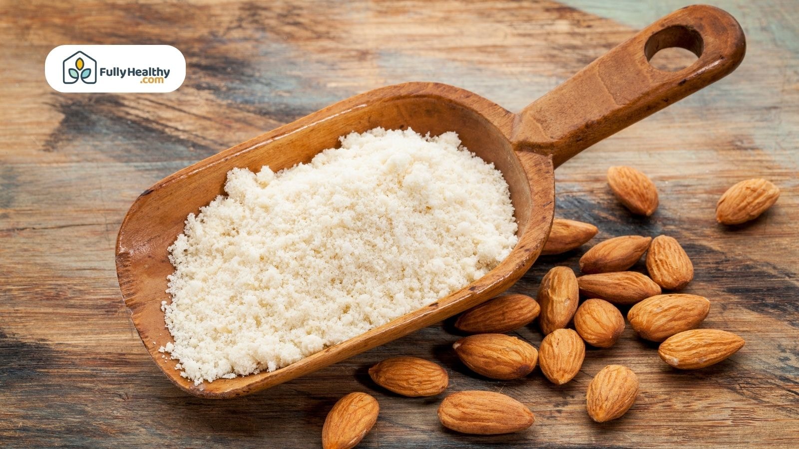 Almond flour in wooden scoop with raw almonds on rustic table