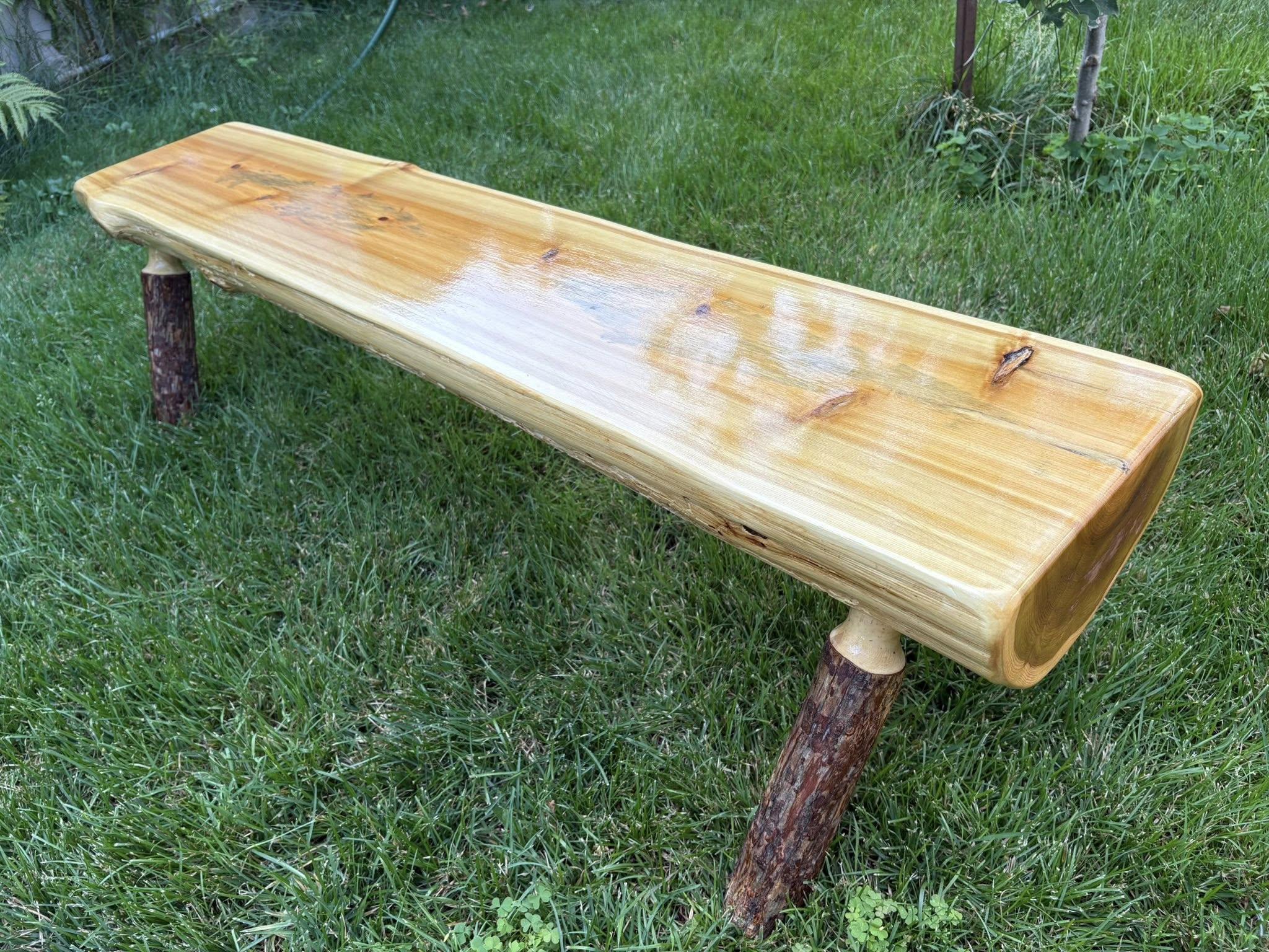 A half log bench sitting on grass. 