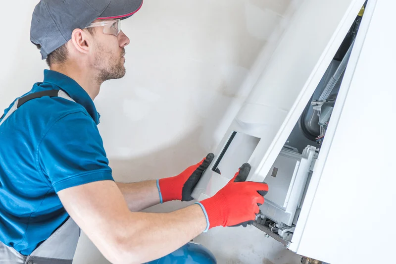 Installateur in Blau mit Schutzhandschuhen repariert eine Wandheizung.
